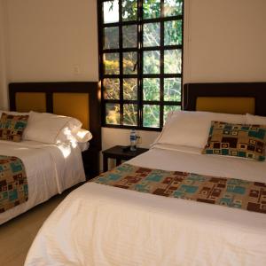 圣奥古斯丁Hotel Campestre El Triunfo的一间卧室设有两张床和窗户。