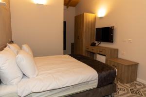 拿撒勒Saint Jacob Hotel的一间卧室配有一张带白色枕头的床和电视。
