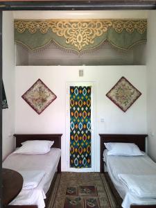 布哈拉Khan Rooms的客房设有两张床和窗户。
