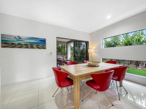 布德林姆Casa Mia Retreat Luxury Family Home on Buderim的一间带木桌和红色椅子的用餐室