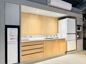 高雄栈贰沐居的厨房配有木制橱柜和白色冰箱。