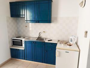 阿佐里姆诺斯Aigaio studios & rooms的厨房配有蓝色橱柜、水槽和冰箱。