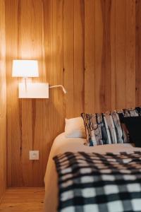 莱代塞尔le chalet de Plainpalais的一间卧室配有一张带灯和木墙的床