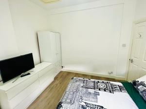 伦敦Cozy apartment in Hampstead Heat的白色的客房配有床和电视。