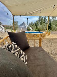 米茨佩·拉蒙KARMEI NEGEV - מתחם גלמפינג ואטרקציות מבית גלובל גלמפינג的一张沙发,坐在带桌子的帐篷下