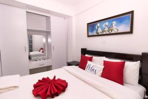 纳纽基Levi's 1 Bedroom Apartment California Plaza Nanyuki的卧室配有带红色枕头的大型白色床
