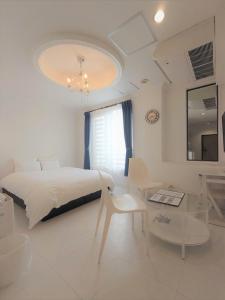 唐津汪洋海上风情度假酒店的白色卧室配有一张大床和一张桌子