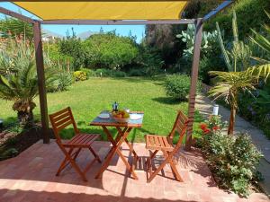 巴勒莫Cozy Suite&Lodge Mondello beach的庭院设有两把椅子和一张带水果的桌子。
