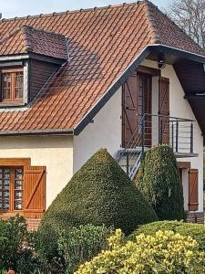 FressennevilleStudio Les Trois Clés的一间有棕色屋顶和灌木的房子