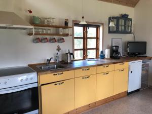 Uggerby桑德加德农家乐的厨房配有黄色橱柜、水槽和炉灶。