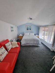 霍尔特The Garden Suite Holt的一间卧室配有一张床和一张红色的沙发