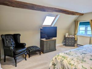 布由德利Worralls Grove Guest Farm House的一间卧室配有一张床、一把椅子和电视。