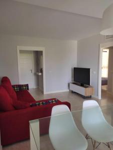 埃尔韦尔赫尔Apartamento bonito - playas las Deveses的客厅配有红色沙发和白色椅子