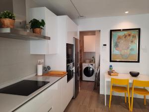 希洪Apartamento Dindurra Centro Playa的厨房配有白色橱柜和桌椅