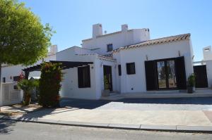 Lo MendigoVilla Vinka - El Valle Golf Resort的白色的房子,有黑窗和车道