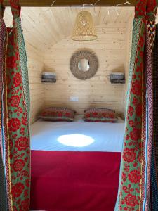 胡菲涅克Les Roulottes de l Herm Piscine Jacuzzi Perigord的木制房间的床,有红色窗帘