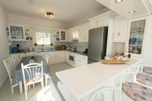波罗斯Rigos House at Askeli beach, Poros island的厨房配有白色橱柜、桌子和冰箱。
