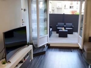 圣西尔-莱科勒Superbe appartement avec jardin proche Versailles的带电视的客厅和天井。