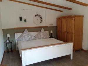 岑平Cottage, Zempin的卧室配有白色的床和木制橱柜。