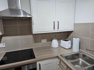 迪德科特1 bed modern flat的厨房配有白色橱柜和水槽