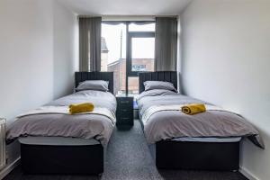 伊斯特伍德Modern flat in Eastwood Town centre的带窗户的客房内设有两张单人床。