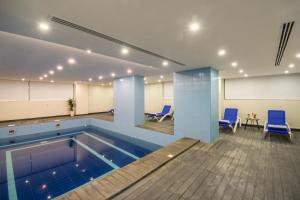 阿可贺巴Enala Hotel - Al Khobar的一个带蓝色椅子和桌子的房间的游泳池