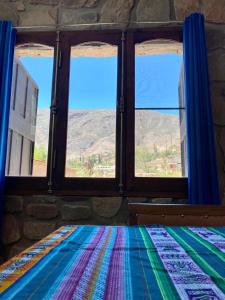 蒂尔卡拉Hospedaje Fortaleza Indigena的客房设有2扇窗户和1张带彩色毯子的床。