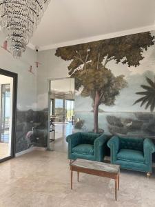 科洛尼亚卡洛斯佩莱格里尼Casimiro Ibera Hotel Boutique的客厅配有2张蓝色的沙发和1个树壁画