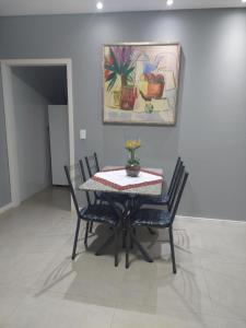 马林加Ótimo apartamento sobreloja com wifi e estacionamento incluso的餐桌、椅子和墙上的绘画