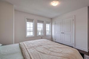 BradfordUnwind Here in a Stylish and Cozy Space的白色卧室设有大窗户和一张大床