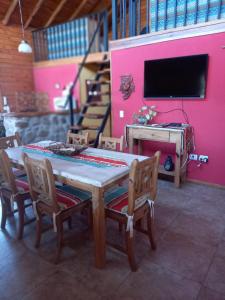 卡皮亚德尔德尔蒙特CABAÑAS ALMA SERENA的粉红色墙壁的房间里一张桌子和椅子