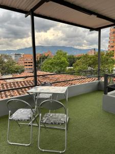 麦德林Aparta estudio amoblado Medellin, San joaquin的屋顶上的一张桌子和两把椅子