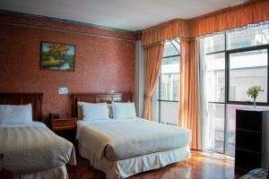 拉巴斯Hotel Diamante Azul的酒店客房设有两张床和窗户。