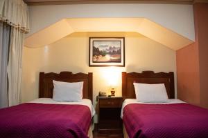 拉巴斯Hotel Diamante Azul的酒店客房,配有两张带紫色床单的床