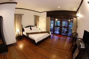 巴色Phubachiang Golf and Resort Pakse的一间卧室配有一张床,铺有木地板