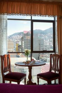 拉巴斯Hotel Diamante Azul的一张桌子和两把椅子位于大窗户前
