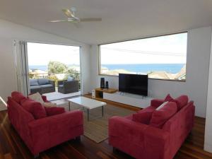 悉尼Clovelly Beach House with Pool的客厅配有2把红色椅子和平面电视