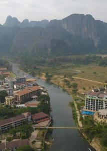 万荣Downtown Vang Vieng Hotel的享有河流的空中景色,拥有建筑和山脉