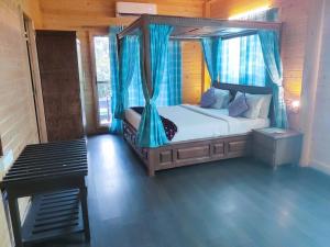 班加罗尔Brahmi Resort的一间卧室配有一张带蓝色窗帘的天蓬床