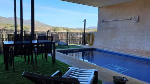 Navas de EstenaCasa con piscina en Parque Nacional de Cabañeros的房屋设有1个带桌椅的游泳池