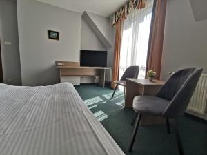 波兹南叶丽涅茨酒店的酒店客房,配有一张床、一张桌子和椅子