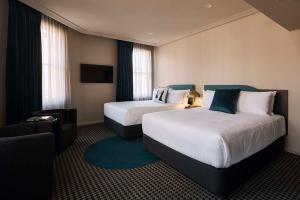 悉尼The Capitol Hotel Sydney的酒店客房设有两张床和电视。