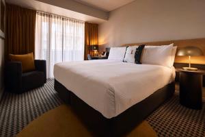 悉尼The Capitol Hotel Sydney的酒店客房带一张大床和一把椅子