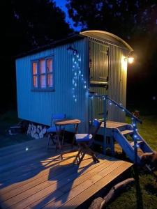 黑尔斯沃思The Warren - Cosy Shepherds Hut in beautiful wild meadow的一座小房子,上面有两把椅子和一张桌子