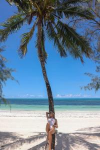 乌罗阿F-Zeen Boutique Hotel Zanzibar的坐在海滩上棕榈树上的女人