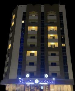 阿吉曼New Royal Palace Hotel Apartments的前面有蓝色标志的高楼