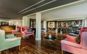 提努姆Relais & Châteaux Landhaus Stricker, Hotel des Jahres 2023的大型客厅配有粉红色的椅子和书籍