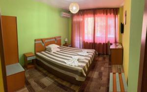 布拉戈耶夫格勒ALPHA family HOTEL的一间设有床铺的卧室,位于一个拥有绿色墙壁的房间