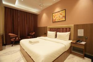 大诺伊达Lime Tree Hotel and Banquet Greater Noida的酒店客房带一张大床和一把椅子