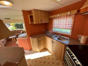 切尔韦尼克拉什托尔Penzión Tulip的厨房配有木制橱柜、水槽和窗户。